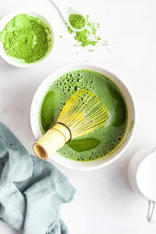 Overhead bowl of freshly whisked matcha with a bamboo chasen